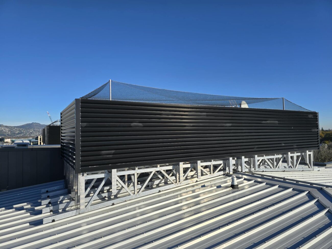 Bird netting installed around rooftop plant on a commercial building